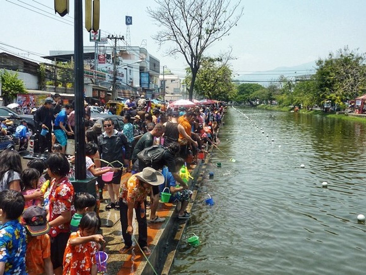 Songkran in Chiang Mai: 2024 Guide To Thailand's Water Festival! | Chiang mai moat songkran Hundreds of people gather around a moat.