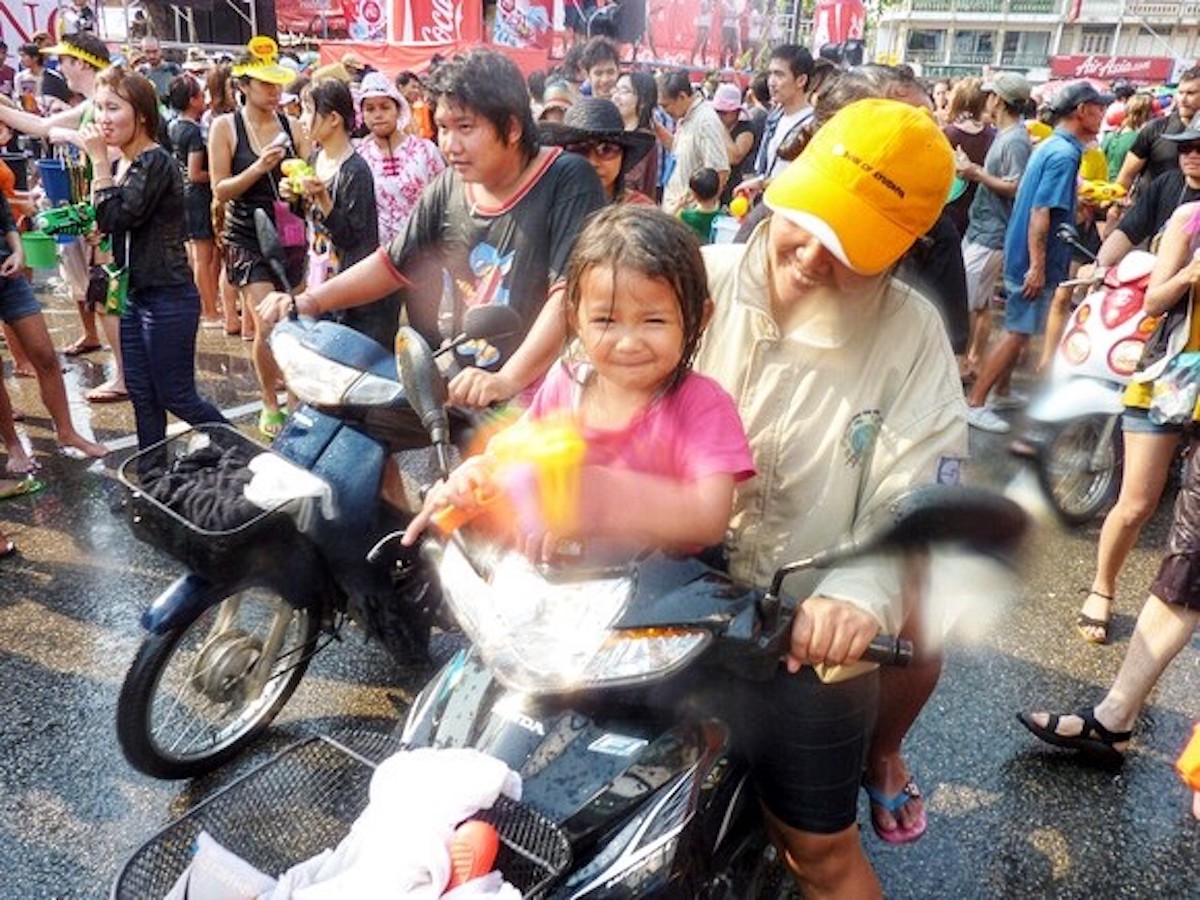 Songkran in Chiang Mai: 2024 Guide To Thailand's Water Festival! | child girl songkran A cute female toddler splashes the camera with a water gun.