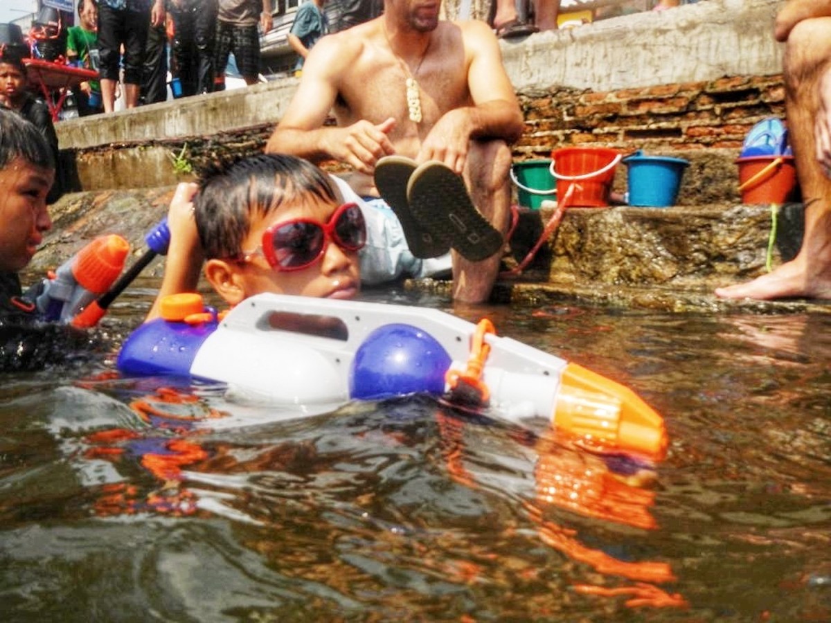 Songkran in Chiang Mai: 2024 Guide To Thailand's Water Festival! | cute kid songkran A young boy in goggles lurks during a water fight.