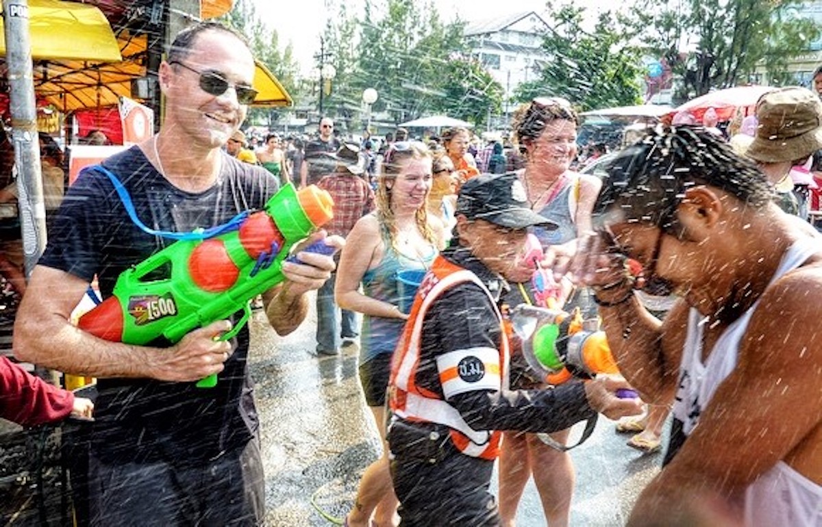 Songkran in Chiang Mai: 2024 Guide To Thailand's Water Festival! | songkran fun 1 A policewoman laughs as people have a water fight.
