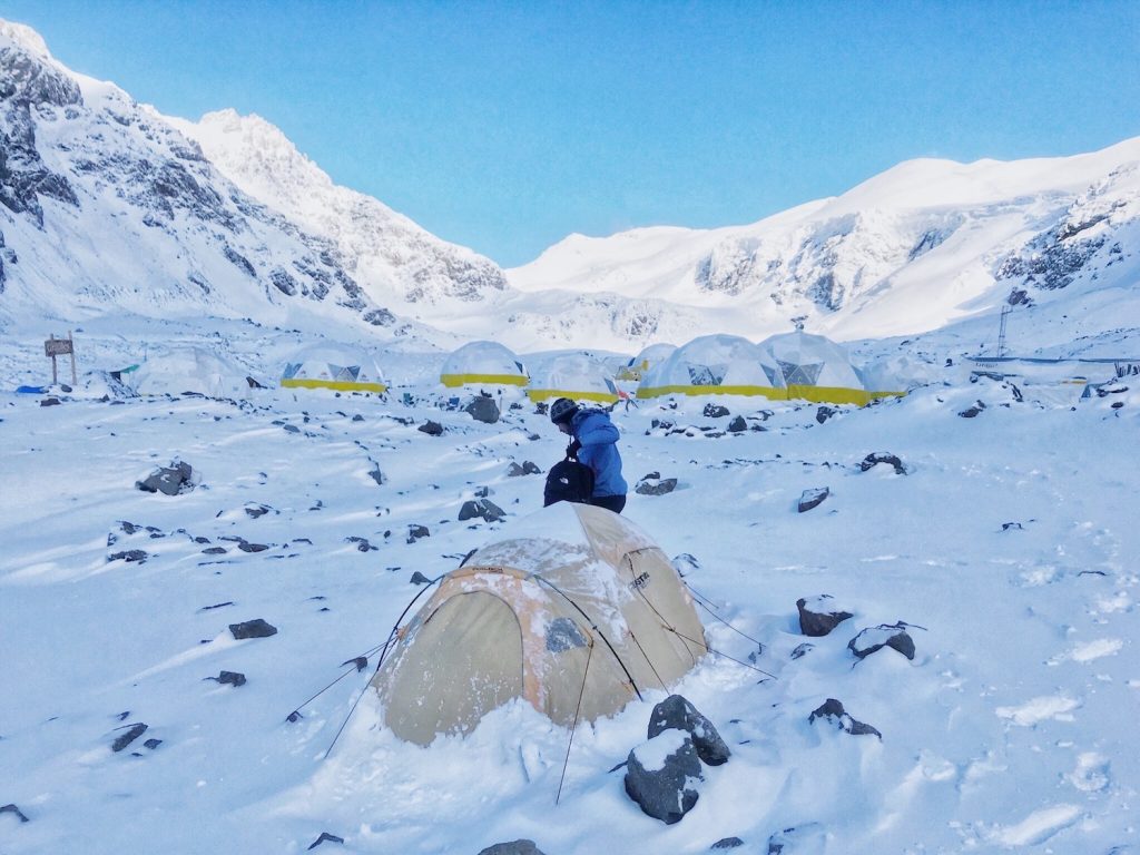 A mountain climber sorts his bag outside his tent in the snow during an Aconcagua failure attempt