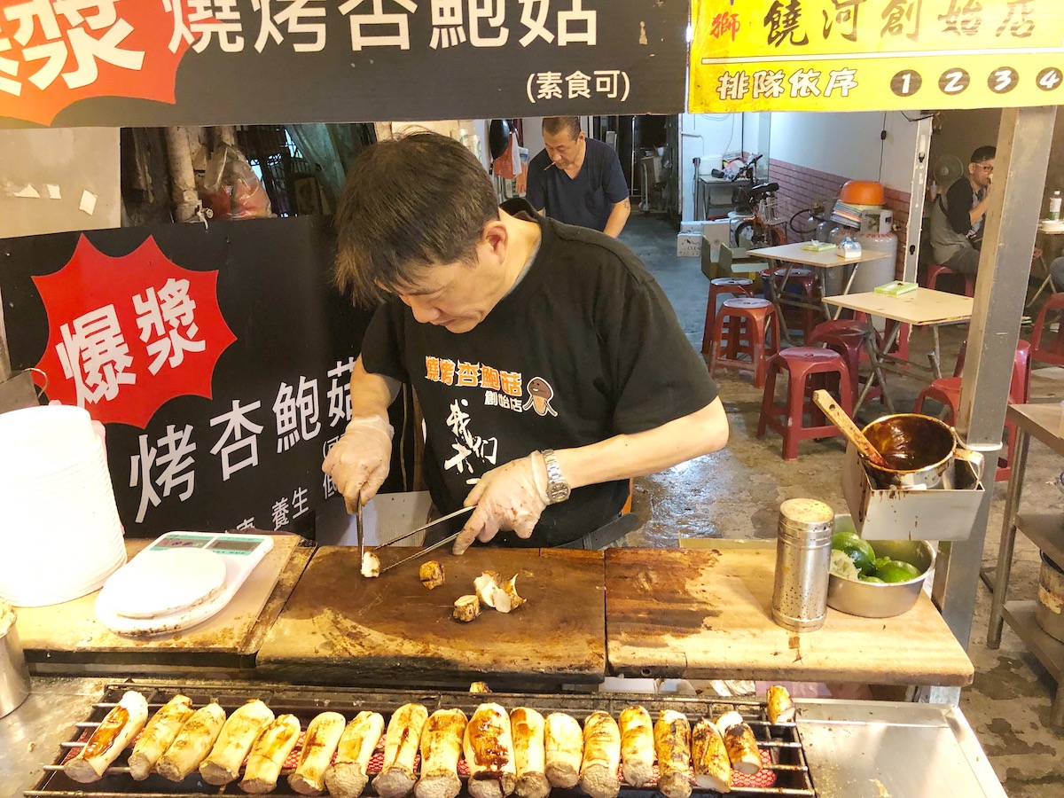 7 Unique & Fun Things To Do in Taipei (Guide For Weirdos!) | Shihlin night market 1 A male street-seller chops up mushrooms to sell in Taipei, Taiwan