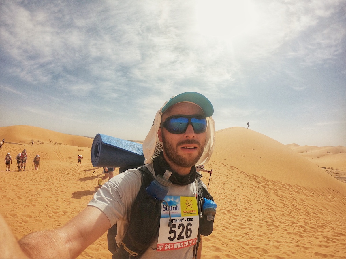 Marathon Des Sables Review: 6 Marathon/6 Days in The Sahara! | Alone in Marathon des Sables man running through desert with sand dunes