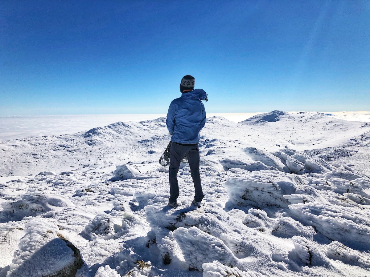 How To Plan The Ultimate Australia Road Trip in 2024 | Kosciuszco national park australia road trip A man standing on top of a snowy mountain holding ski shoes.