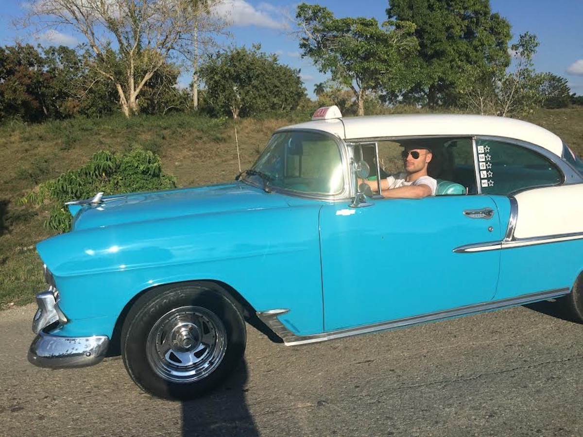 The Only Road Trip Packing List You'll Ever Need! | road trip packing list A man in a classic blue and white Chevrolet gets ready for a road trip in Cuba