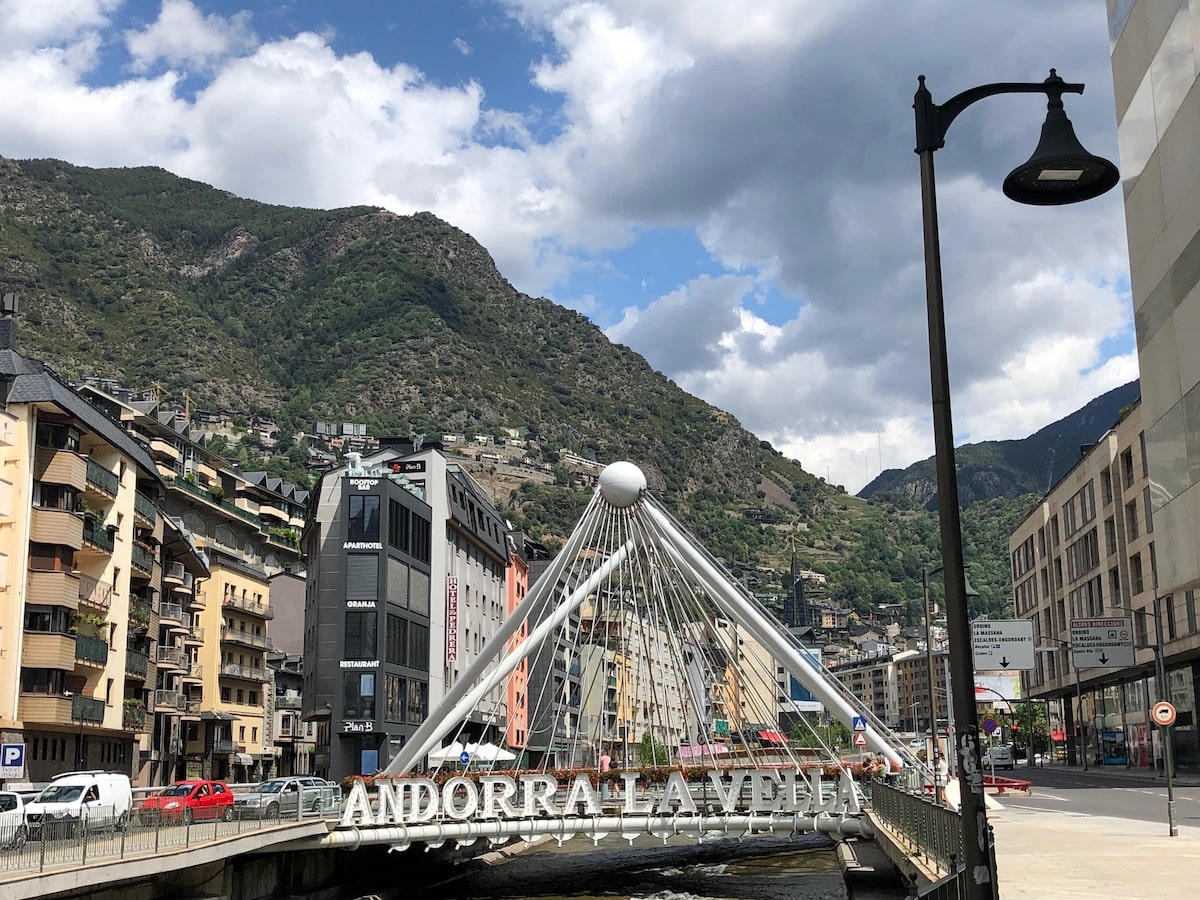 A Handy Guide To The 6 Microstates of Europe | Andorra la vella Signpost of Andorra la vella with a large green mountainous hill behind it