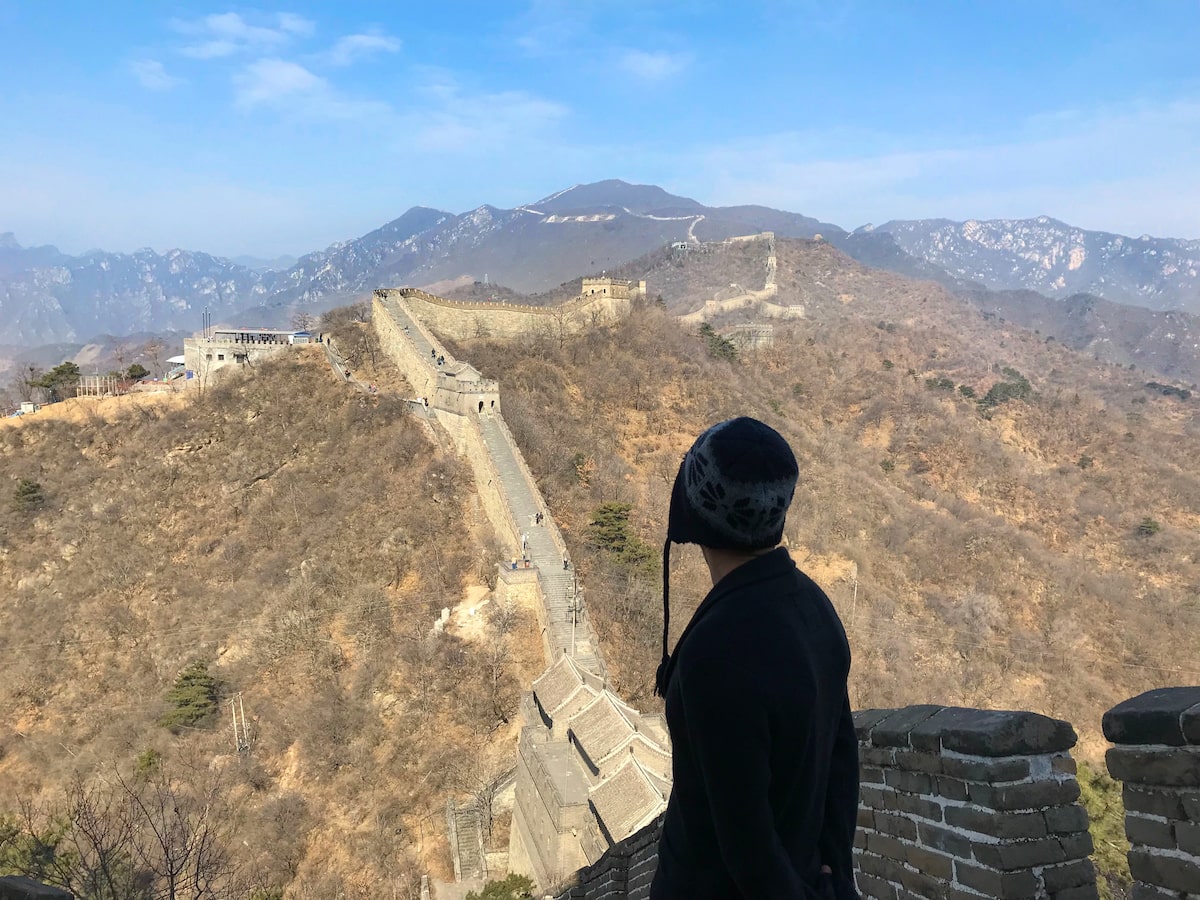Best Place To See Great Wall of China (No Crowds, No Worries!) | Best place to see Great Wall of China A tourist looks out into a landscape of the Great Wall of China.