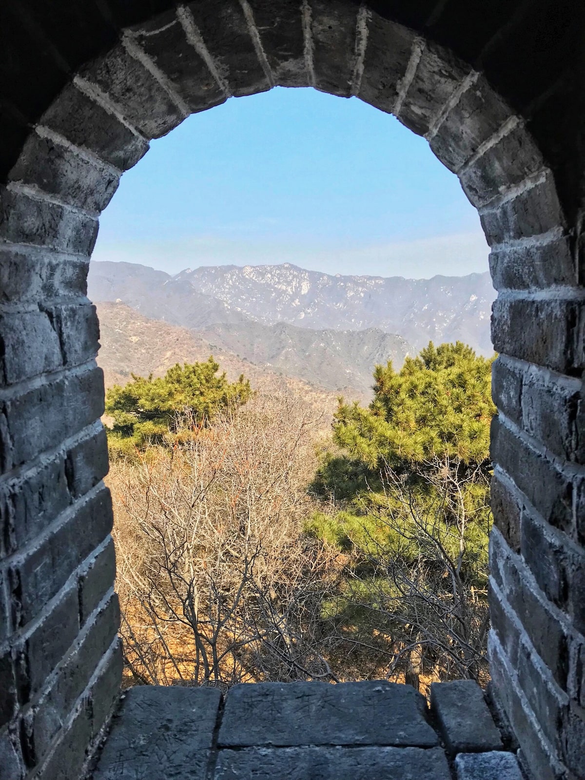 Best Place To See Great Wall of China (No Crowds, No Worries!) | Great Wall of China best place An archway looking out into mountains and trees.