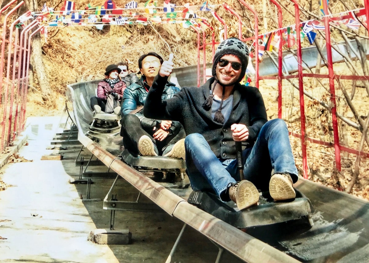 Best Place To See Great Wall of China (No Crowds, No Worries!) | Mutianyu toboggan ride A man in a hat smiles at the bottom of a toboggan ride.