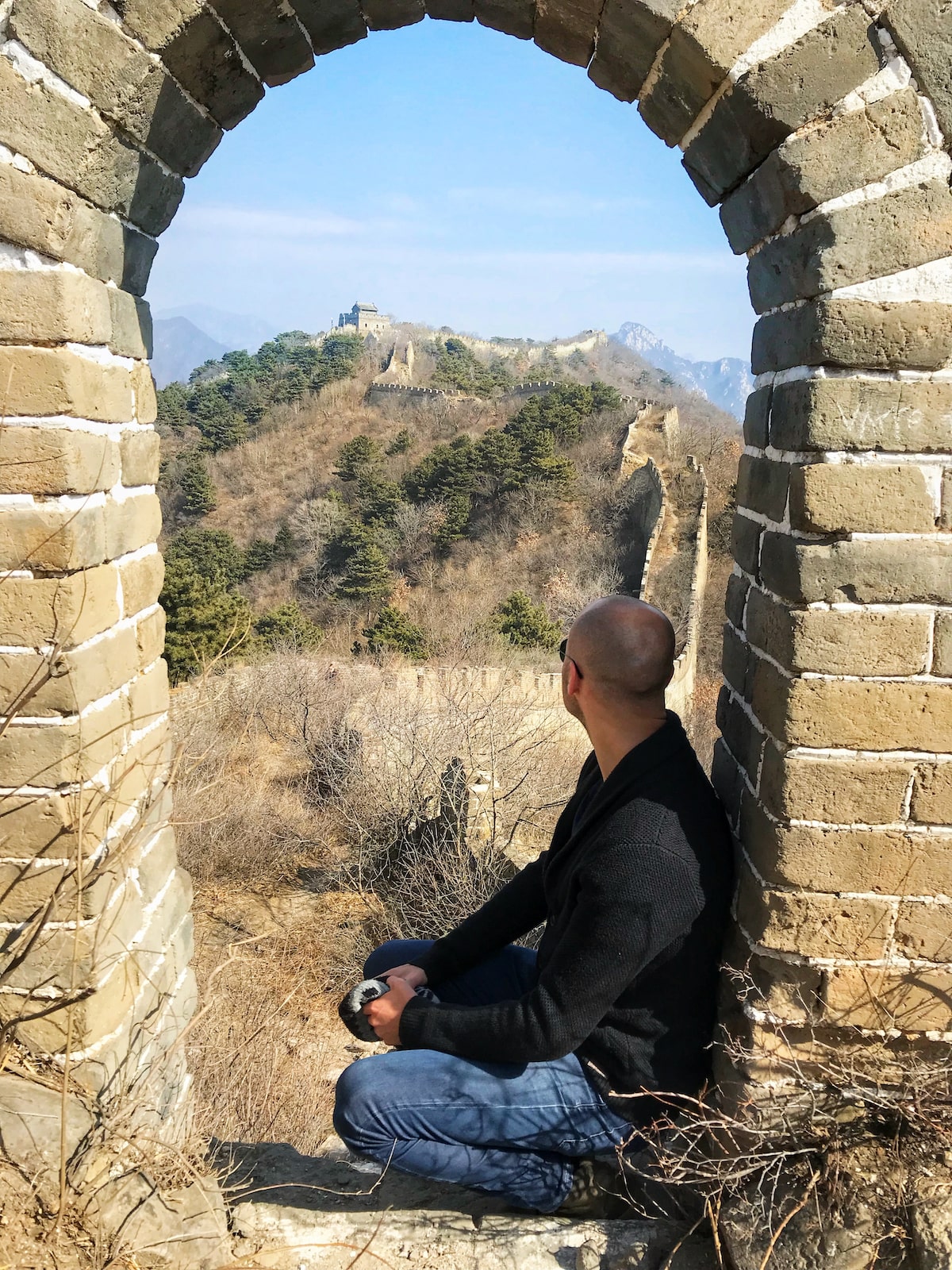 Best Place To See Great Wall of China (No Crowds, No Worries!) | The Wild Great Wall of China A male tourist looks out into The Great Wall of China from an archway on a sunny day in Beijing.