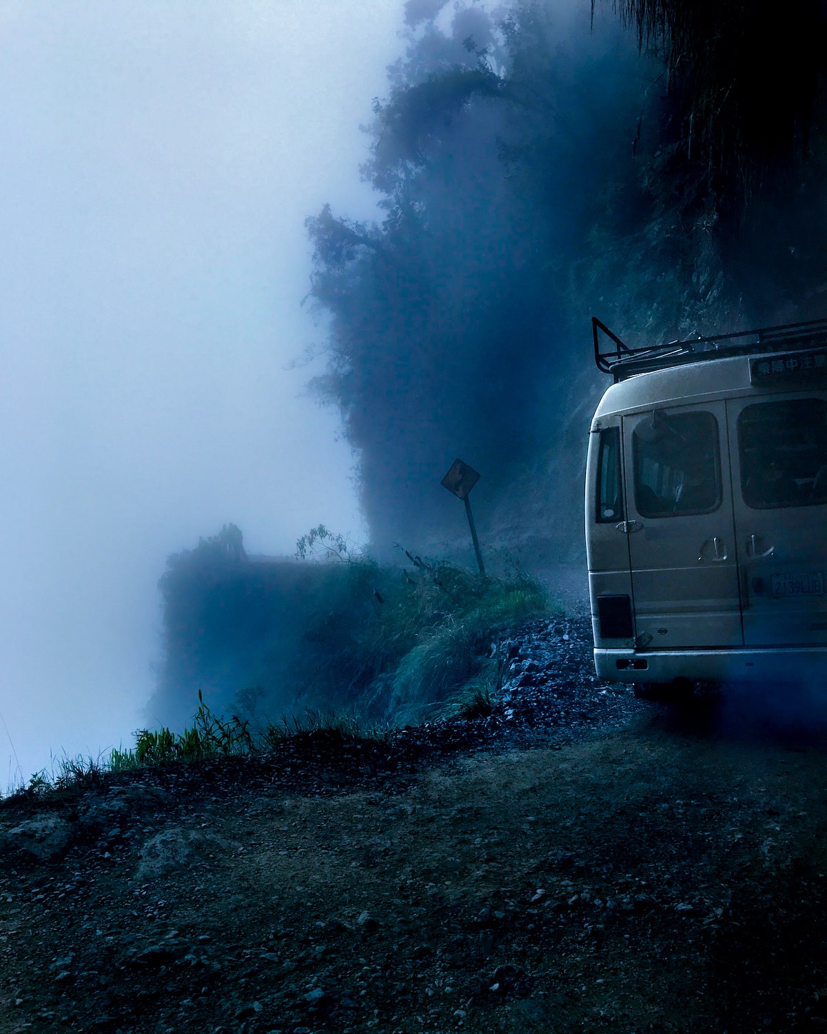 Cycling Down Bolivia's Death Road (How Not To Die!) | van death road in Bolivia A van drives over a tight bend on a cliff with no barriers on Bolivia's Death Road.