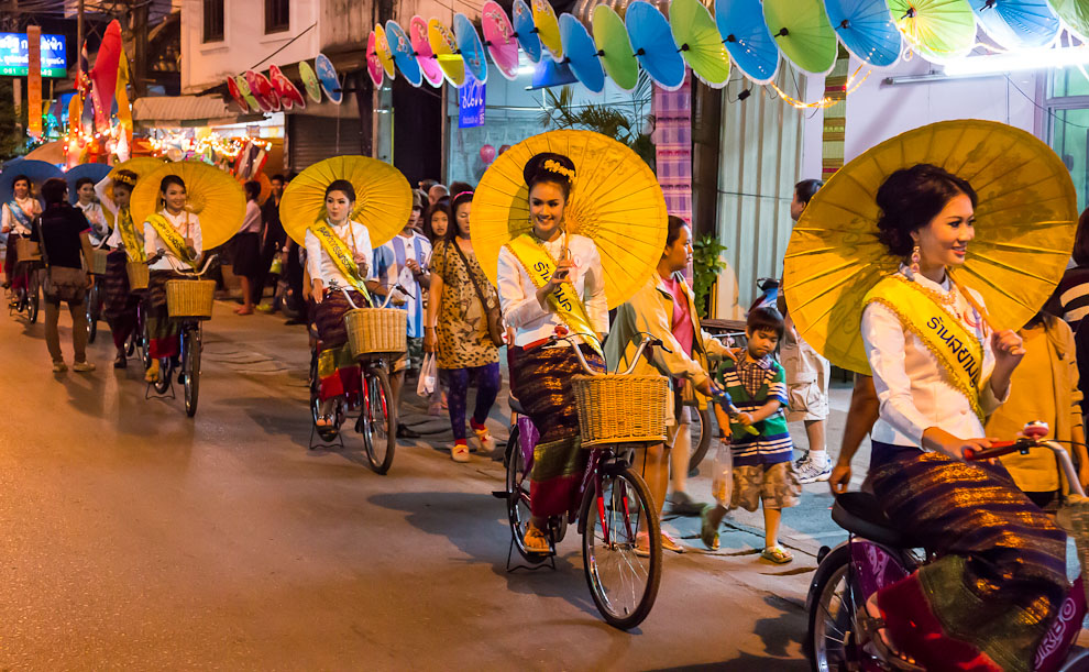 17 Best Thailand Festivals (That You May Never Heard Of) | Bor Sang Umbrella Festival Pretty Thai ladies drive bicycles while holding large umbrellas in one of the best festivals in Thailand.