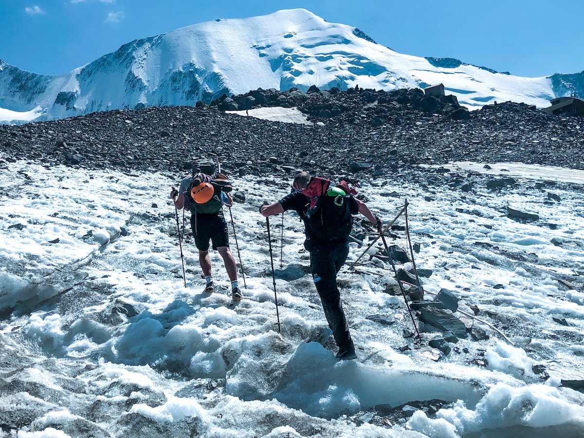 Mont Blanc Climb (The Beginner's Guide To Summiting in 2024) | Chamonix Mont Blanc tour Two men with walking poles battle through the ice in Mont Blanc, France.