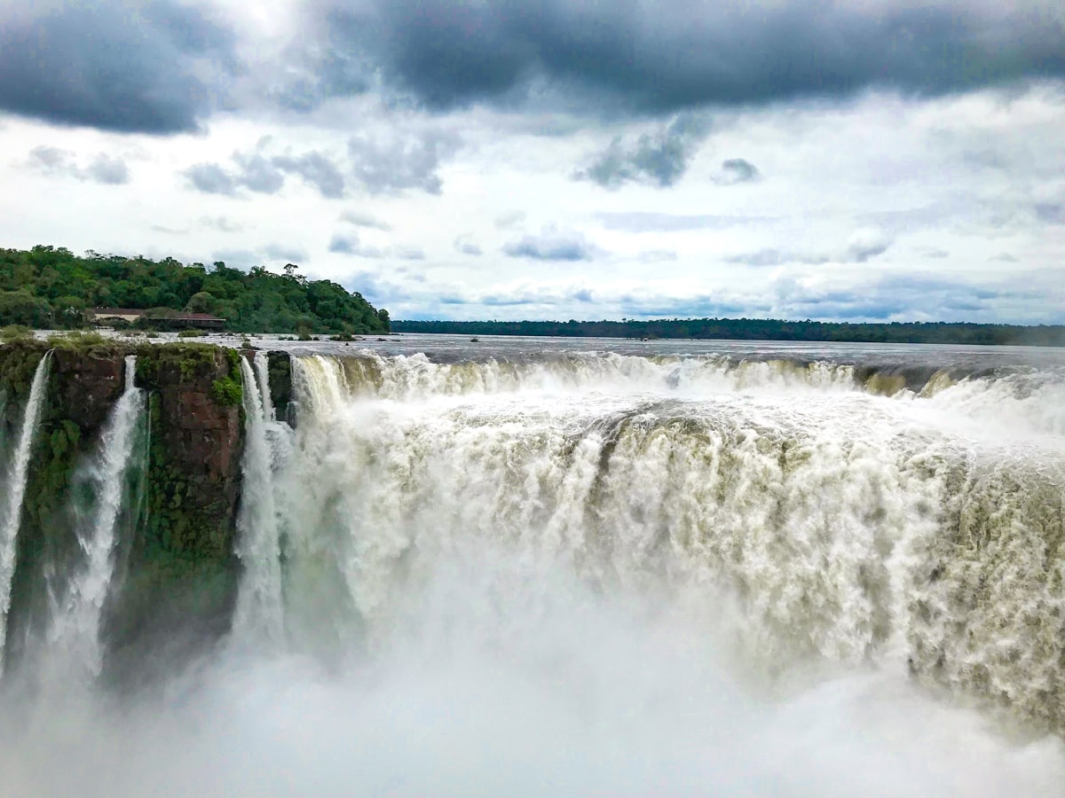 The Ultimate Guide To Visiting Both Sides of Iguazu Falls | Devils throat Iguazu A giant waterfall in Iguazu Falls on a moody day in Argentina
