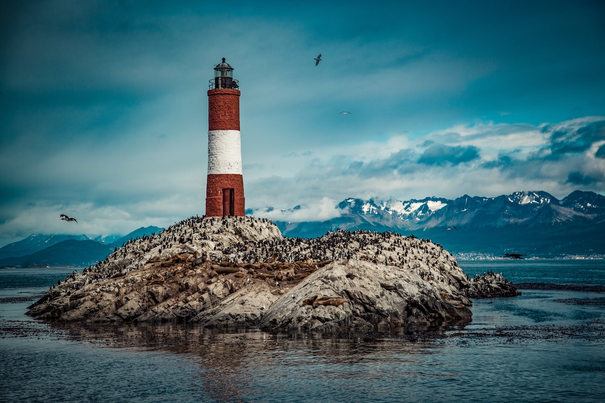 23 Best Things To Do in Ushuaia, Argentina | Faro Les Eclaireurs Lighthouse A red and white lighthouse on a body of water