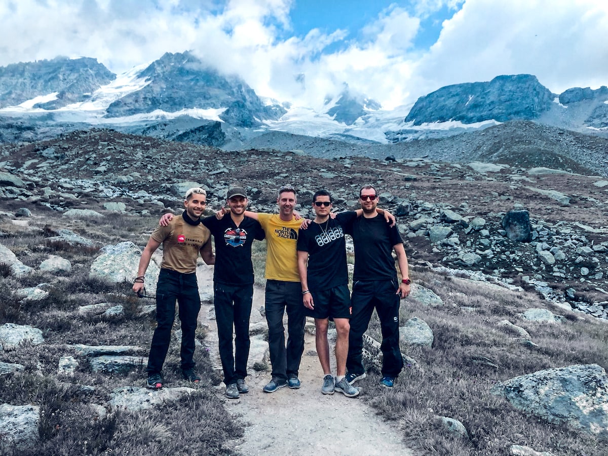 Mont Blanc Climb (The Beginner's Guide To Summiting in 2024) | Group tour Mont Blanc Five men with arms on each other's shoulders pose in the French Alps in front of icy, snow-capped mountains.