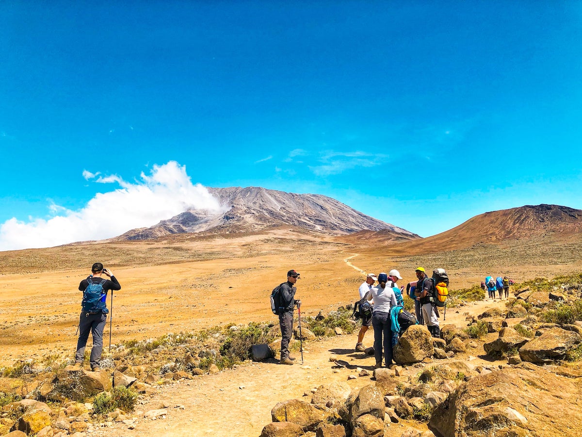 The Beginner's Guide To Climbing Mount Kilimanjaro | High up on Mount Kilimanjaro Climbers gather around a trail as they begin to climb Mount Kilimanjaro.