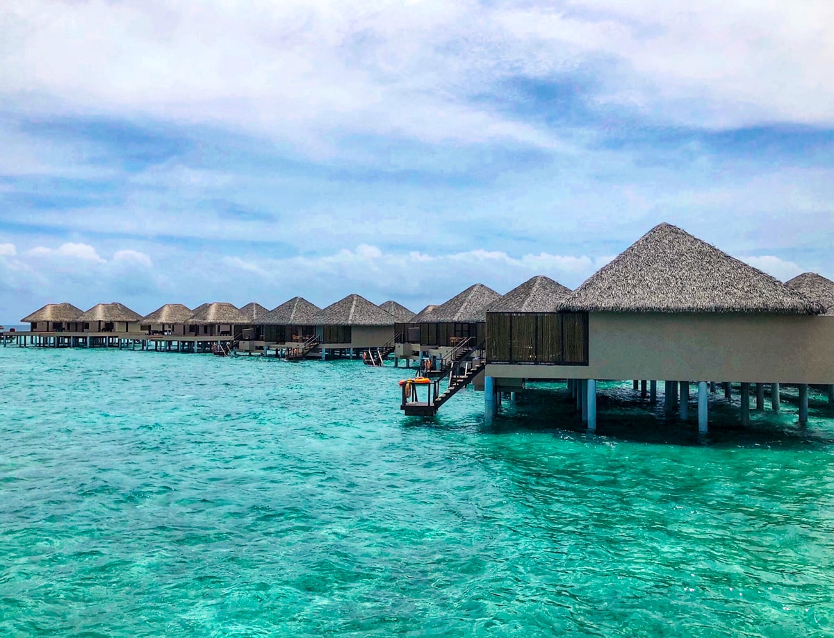 How To Plan a Trip To The Maldives | How to plan a trip to Maldives A landscape view of water bungalows in a Maldives resort overlooking turquoise blue sea