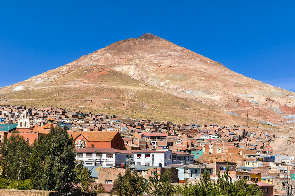 28 Best Things To Do in La Paz, Bolivia & Surrounding Areas | Huayna Potosi A brown mountain towers over a busy neighbourhood in La Paz, Bolivia.