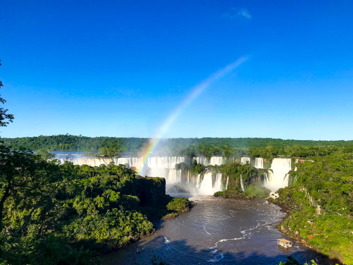 The Ultimate Guide To Visiting Both Sides of Iguazu Falls | Iguazu Falls Brazil side A beautiful landscape view of a rainbow going over Brazil Iguazu Falls
