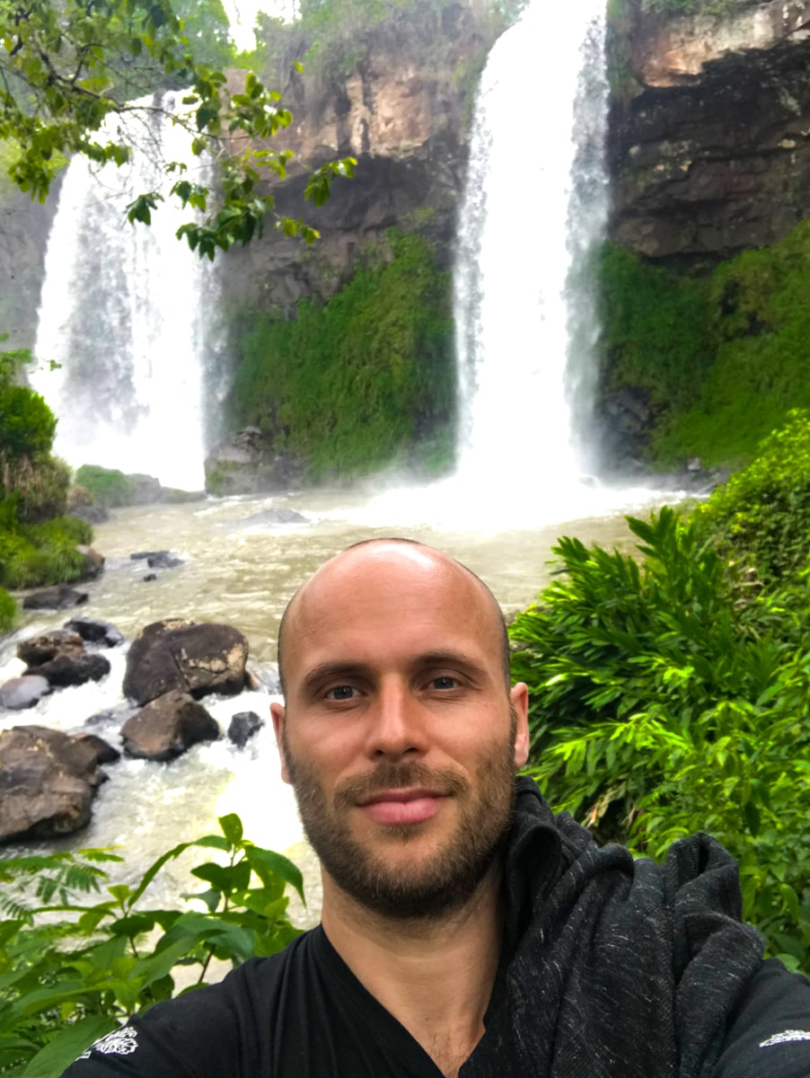 The Ultimate Guide To Visiting Both Sides of Iguazu Falls | Iguazu Falls Solo A man takes a selfie near two waterfalls