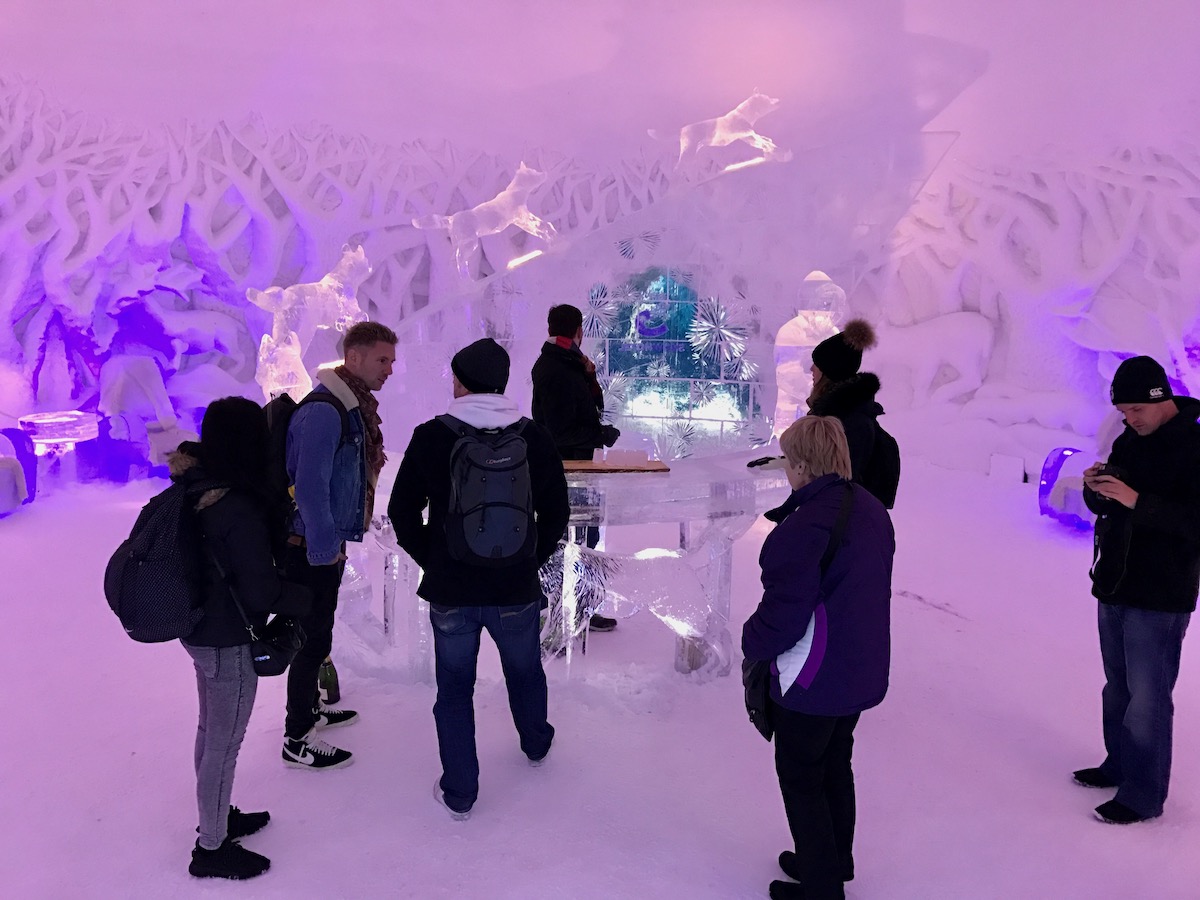 Staying in The Kirkenes Snow Hotel in Norway (Bucket List!) | Kirkenes Snow Hotel bar A group of tourists in an ice bar in the Snowhotel of Kirkenes in Norway's Arctic Circle.