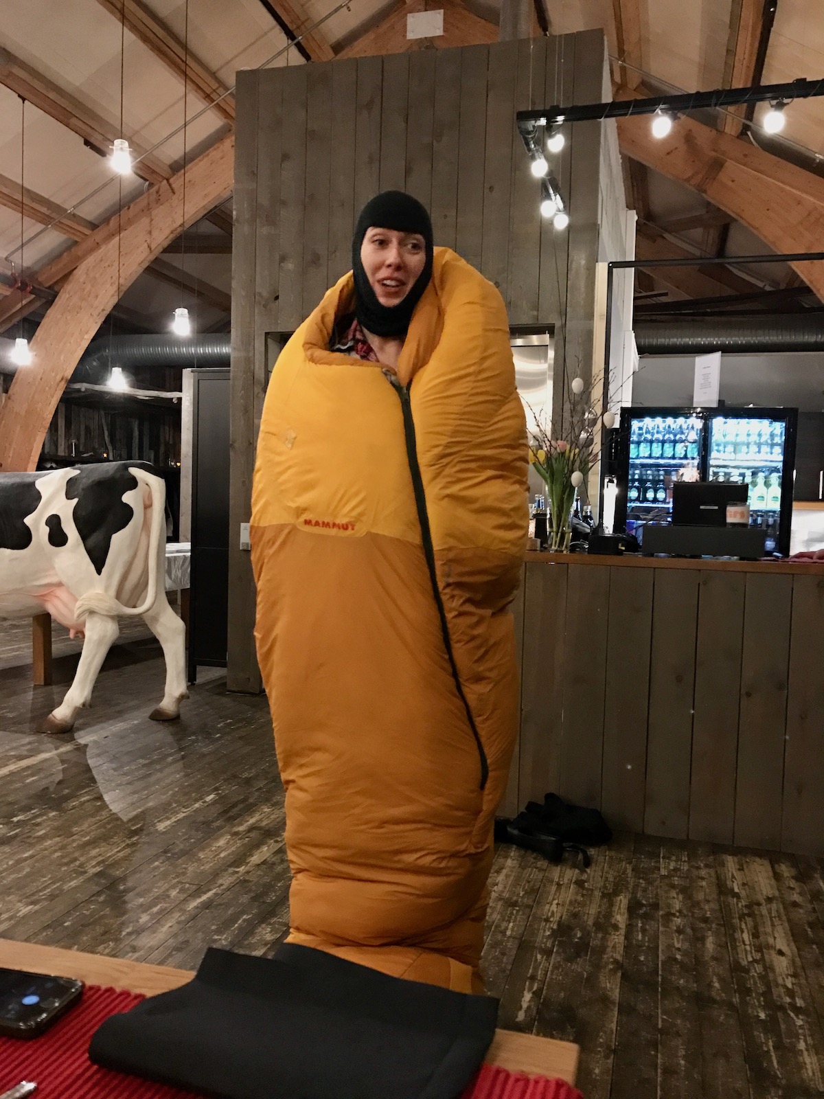 Staying in The Kirkenes Snow Hotel in Norway (Bucket List!) | Kirkenes Snow Hotel staff A female guide wrapped in a sleeping bag explains how to stay warm while sleeping in an ice hotel in Norway