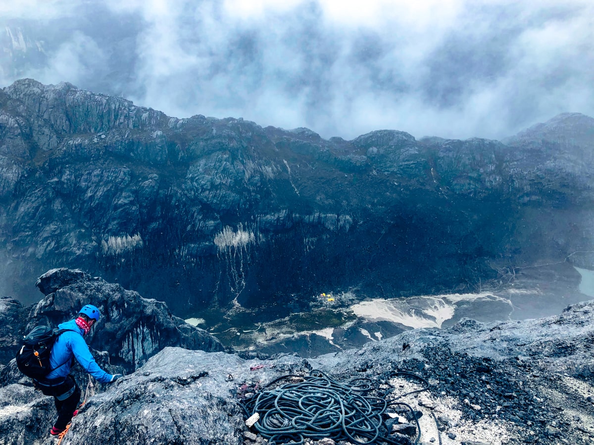 Climbing Puncak Jaya: How To Summit Carstensz Pyramid | Man climbing Puncak Jaya amazing view A male climber on Puncay Jaya with a beautiful misty landscape in the background