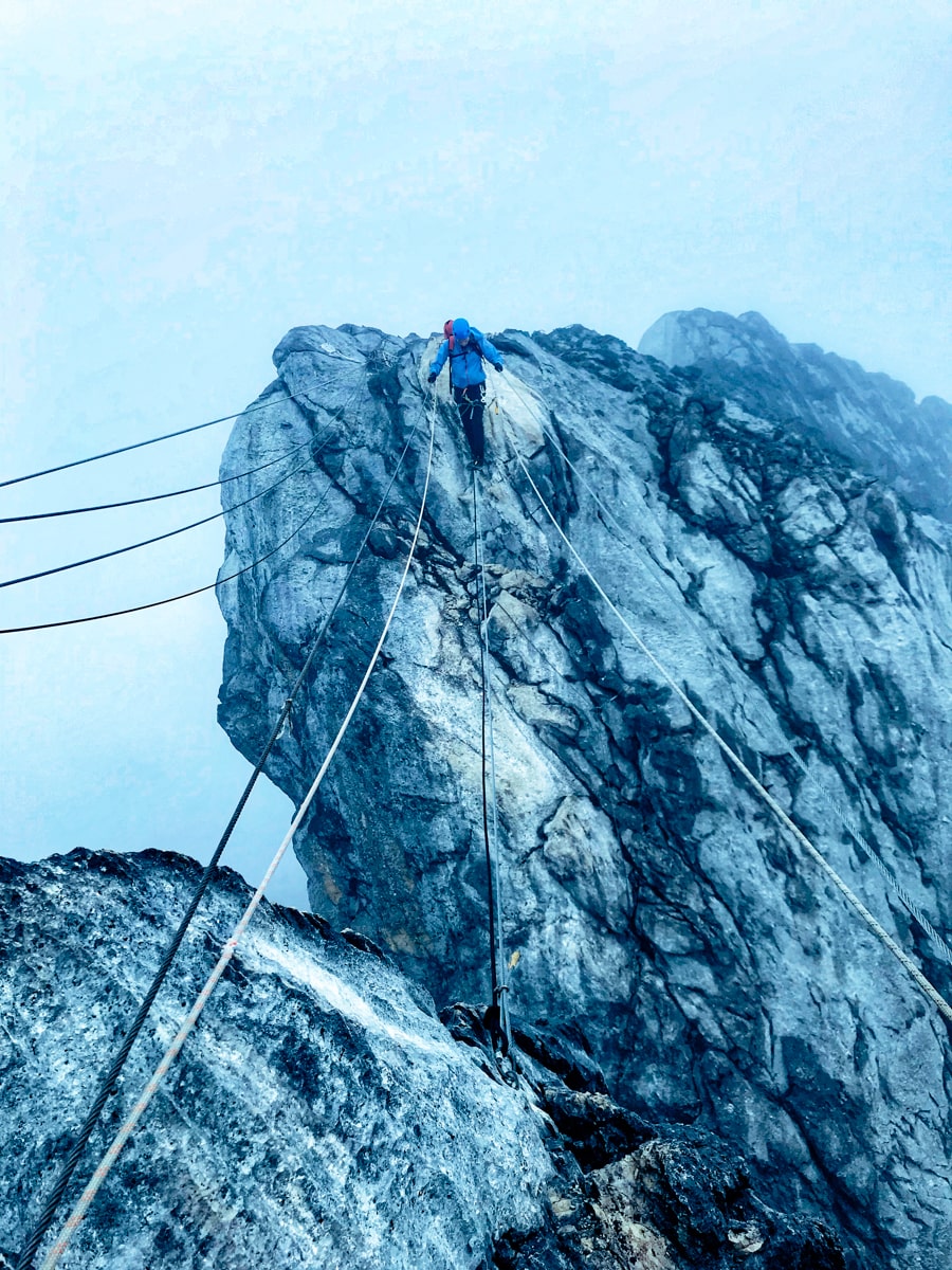 Climbing Puncak Jaya: How To Summit Carstensz Pyramid | Man crossing rope bridge Puncak Jaya A climber braces himself for the rope bridge on Puncak Jaya