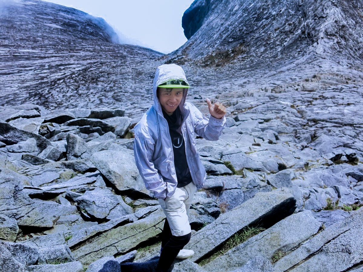 Climbing Mount Kinabalu Tips & Info For First-TimersĀ | Mount Kinabalu guide A male mountain guide smiles with a thumb up on Mount Kinabalu, Malaysian Borneo.
