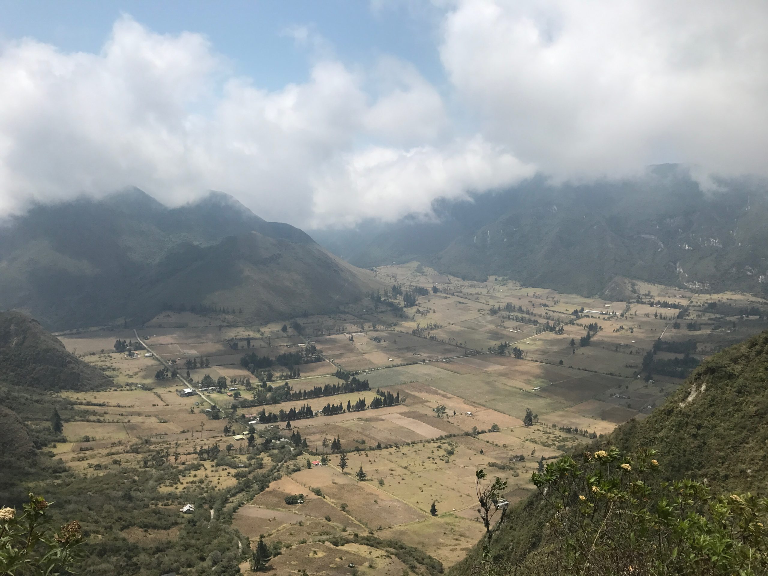 One Week in Quito, Ecuador: 23 Things in 7 Days! | Pululahua Geobotanical Reserve scaled Misty clouds overlook large green mountains and fields in Quito, Ecuador.