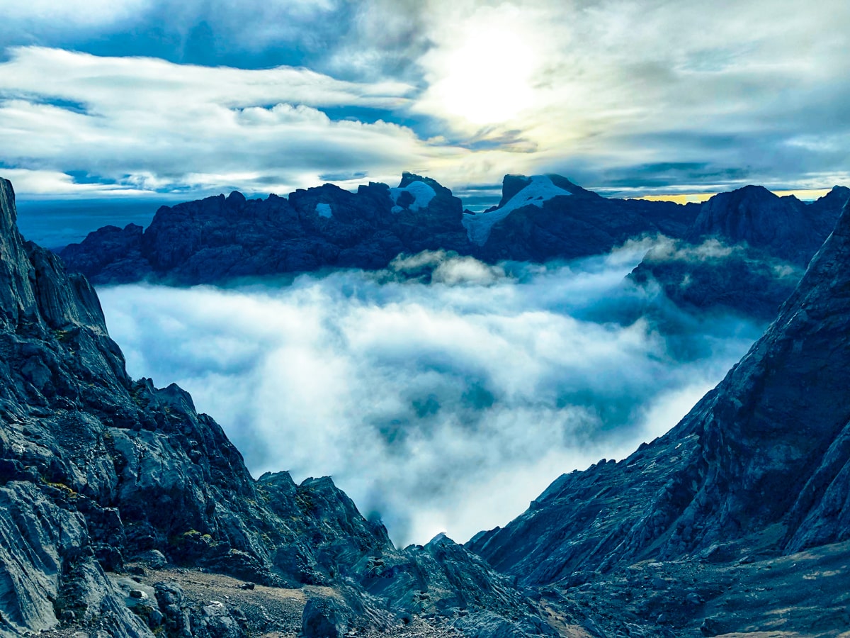 Climbing Puncak Jaya: How To Summit Carstensz Pyramid | Puncak Jaya Carstensz Pyramid Moody clouds hang over the horizon of a cloud-filled mountain in Puncak Jaya, Indonesia.