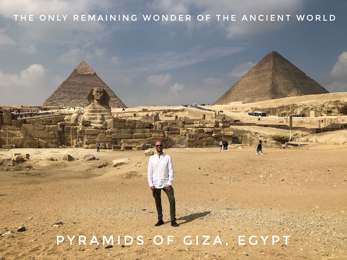 Ranking The New Seven Wonders Of The World From Worst To Best | Pyramids of Giza remaining ancient world wonder Man in white shirt and sunglasses poses in front of the Pyramids of Giza, Egypt.