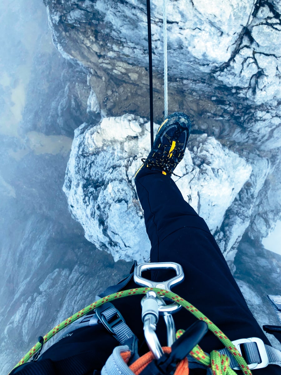 Climbing Puncak Jaya: How To Summit Carstensz Pyramid | Rope view climbing Puncak Jaya View below a man stepping over a rope on Puncak Jaya mountain