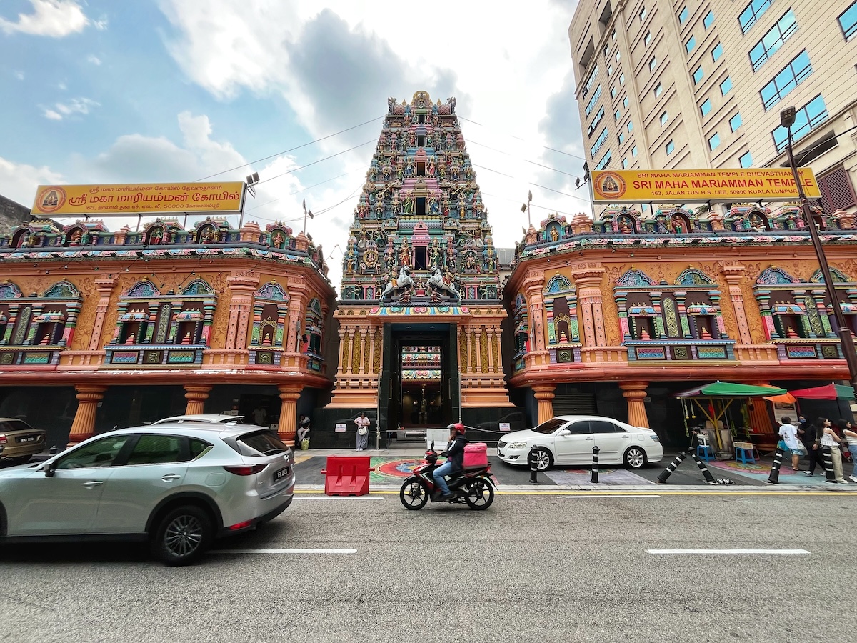 How Many Days Should You Spend in Kuala Lumpur? | Sri Maha Mariamman Temple Colourful and ornate Sri Maha Mariamman Temple in Kuala Lumpur, Malaysia, with detailed sculptures and vibrant decorations, flanked by city buildings. Motorists pass by on the street in front of the temple