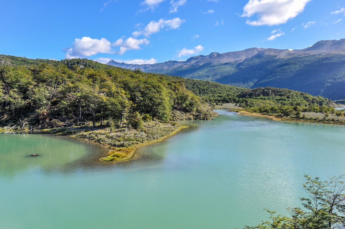 23 Best Things To Do in Ushuaia, Argentina | Tierra del Fuego National Park Lush green hills on a body of water in Tierra del Fuego National Park, Ushuaia, Argentina