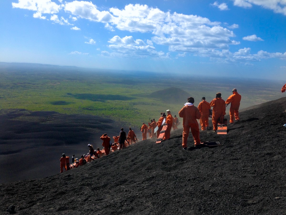 Volcano in Boarding in Leon, Nicaragua (Cerro Negro) | Tour Cerro Negro A tour group in orange jumpsuits hold their boards on a volcano.