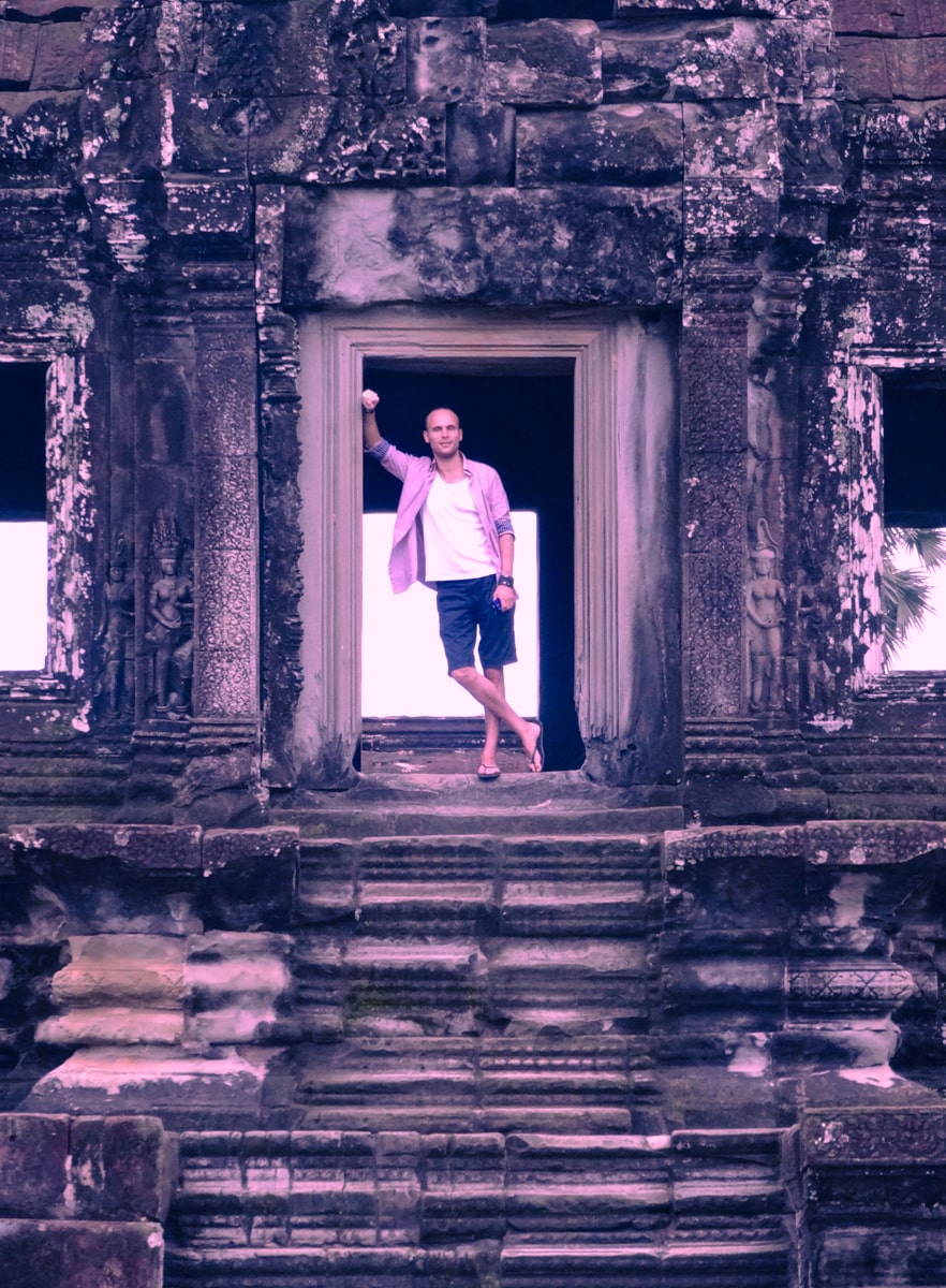 Visiting Angkor Wat: How To Avoid The Crowds | Tourist poses at Angkor Wat archway Tourist at Angkor Wat without crowds