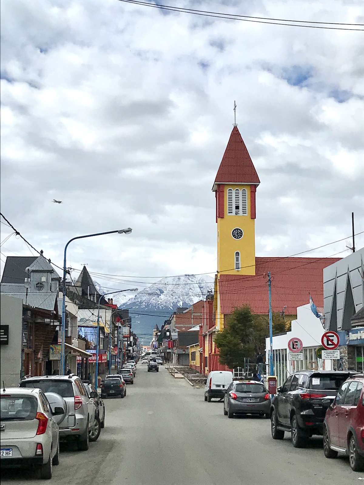 23 Best Things To Do in Ushuaia, Argentina | Ushuaia town Cars park up alongside a town with snpw-capped mountains in the background in Ushuaia, Argentina