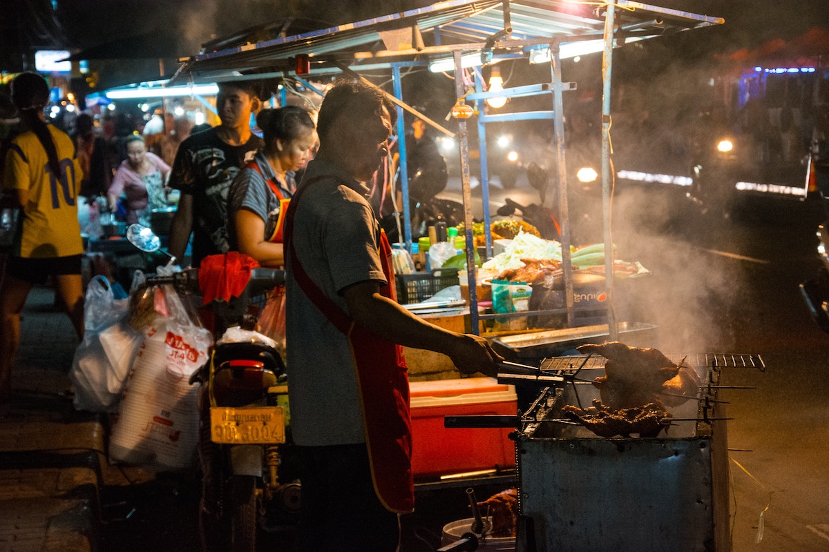 15 Things To Do in Vientiane, Laos (Includes Day Trips) | Vientiane Night Market A man fries chicken in a street market in Vientiane, Laos