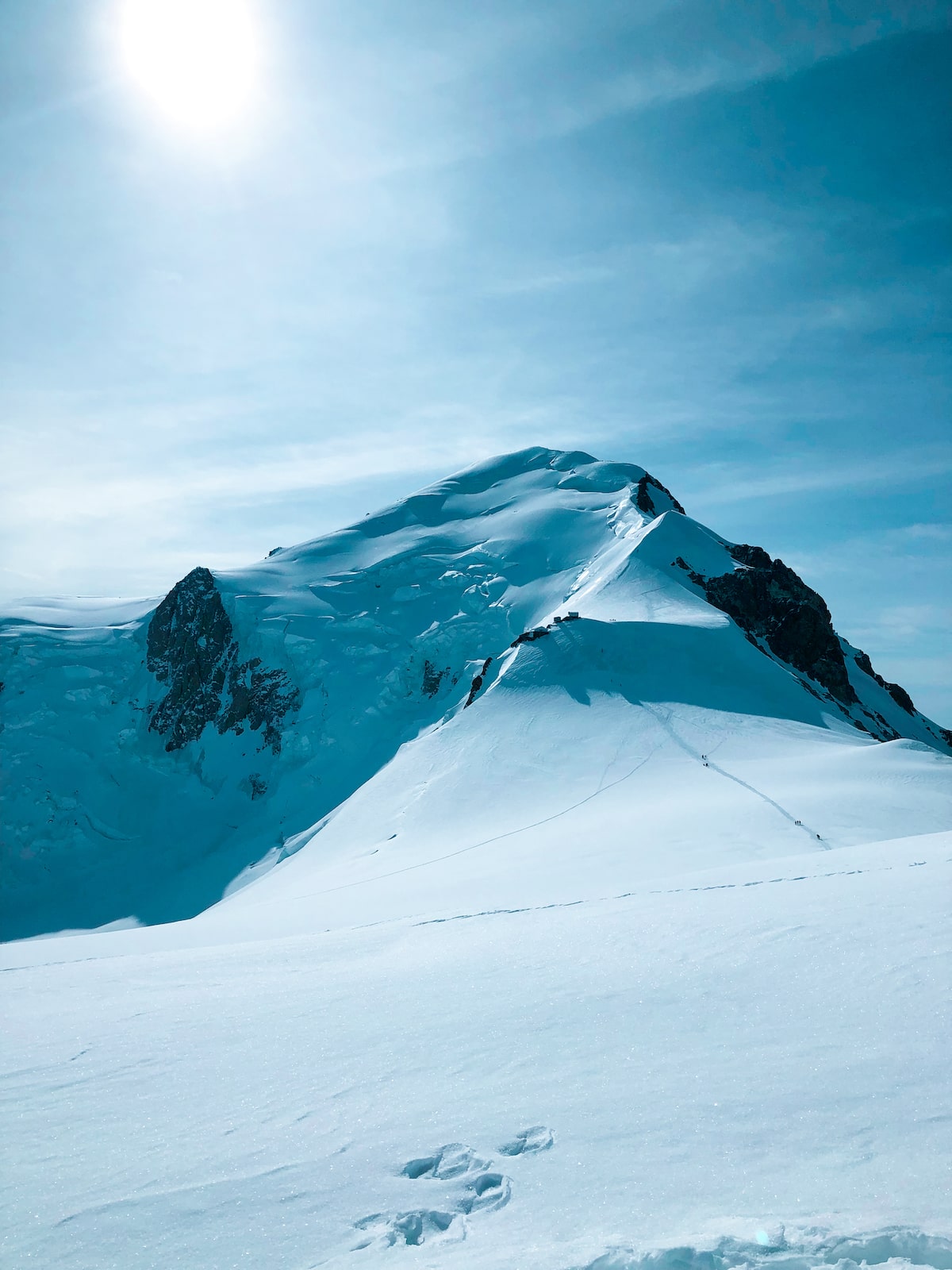 Mont Blanc Climb (The Beginner's Guide To Summiting in 2024) | View from Gouter Hut Route A snowy mountain with footprints from hikers.