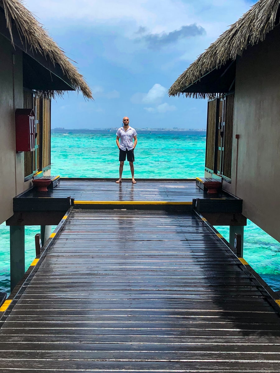 How To Plan a Trip To The Maldives | Visiting Maldives A male tourist poses between two water villas in the beautiful Maldives