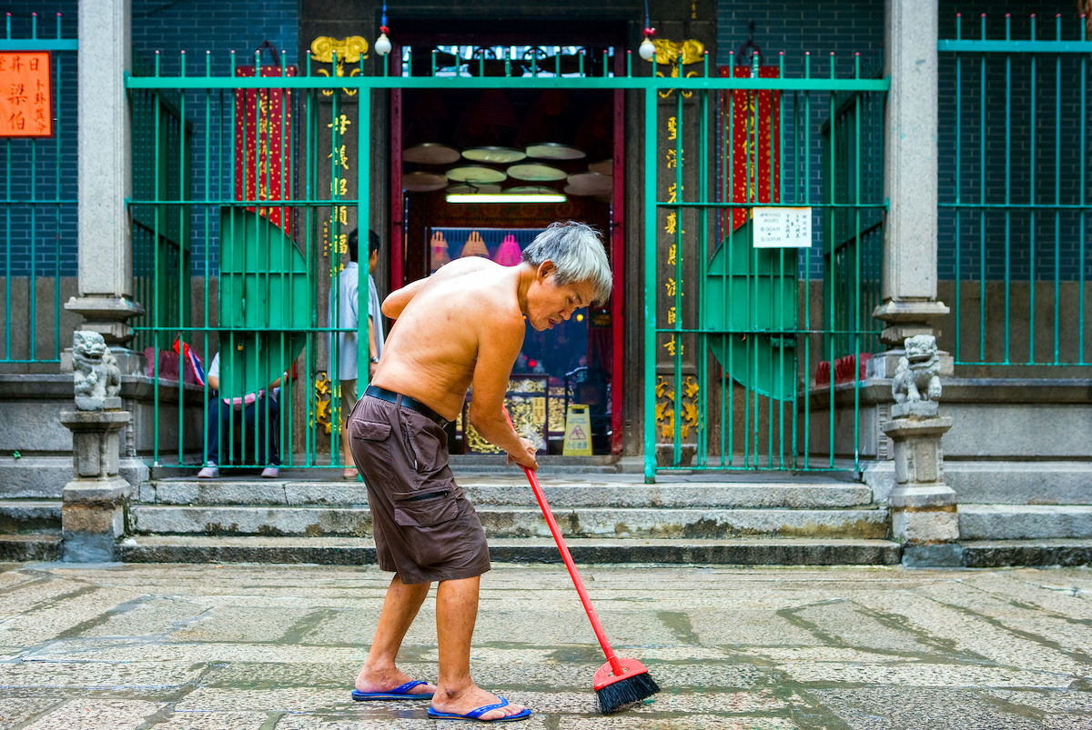 The Ultimate Hong Kong Bucket List: 25 Best Things To Do! | Yau Ma Tei Tin Hau Temple An old man sweeps the entrance of the Tin Hau Temple in the Yau Ma Tei quarter