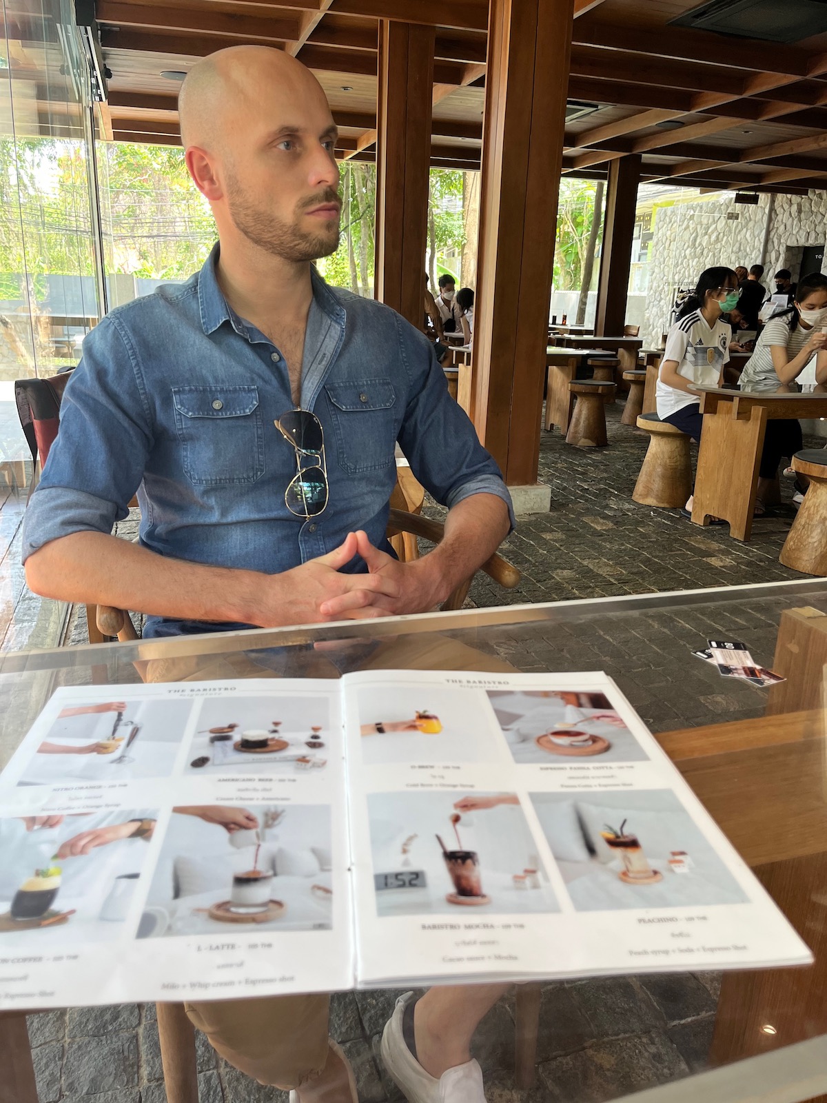 Detailed Chiang Mai Digital Nomad Guide For 2024 | cafe in Chiang Mai 1 A man with a shaved head and beard looks to the side while waiting in a cafe in Chiang Mai