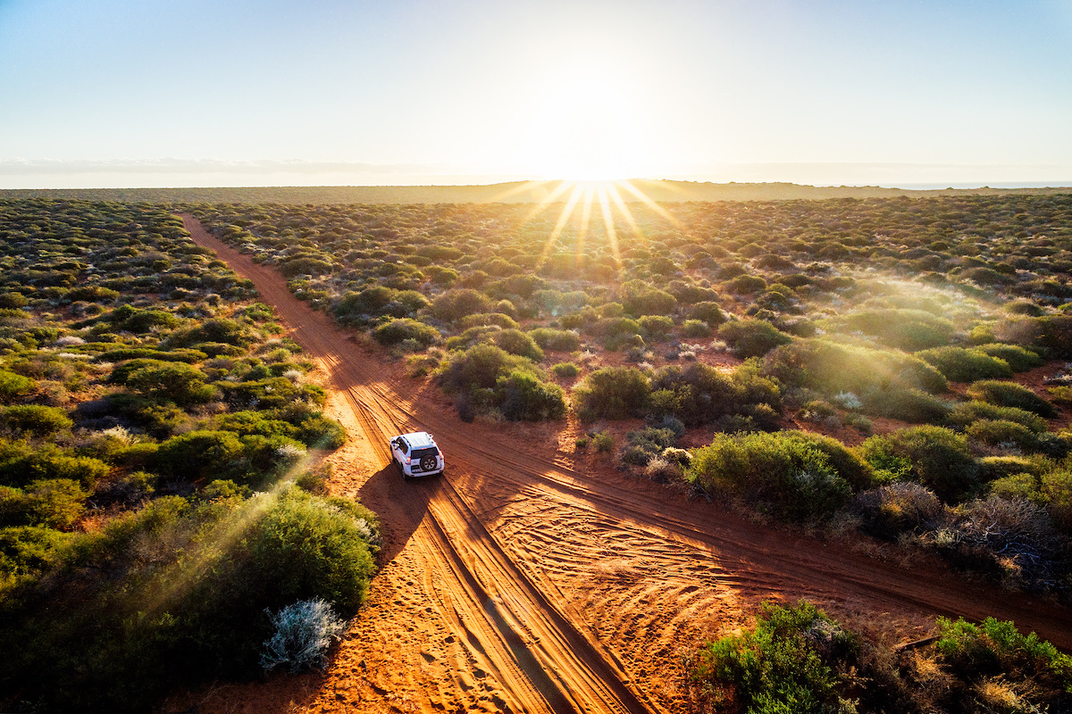 How To Plan The Ultimate Australia Road Trip in 2024 | campervan in australia A campervan driving through the desert on a sunny day in Australia.