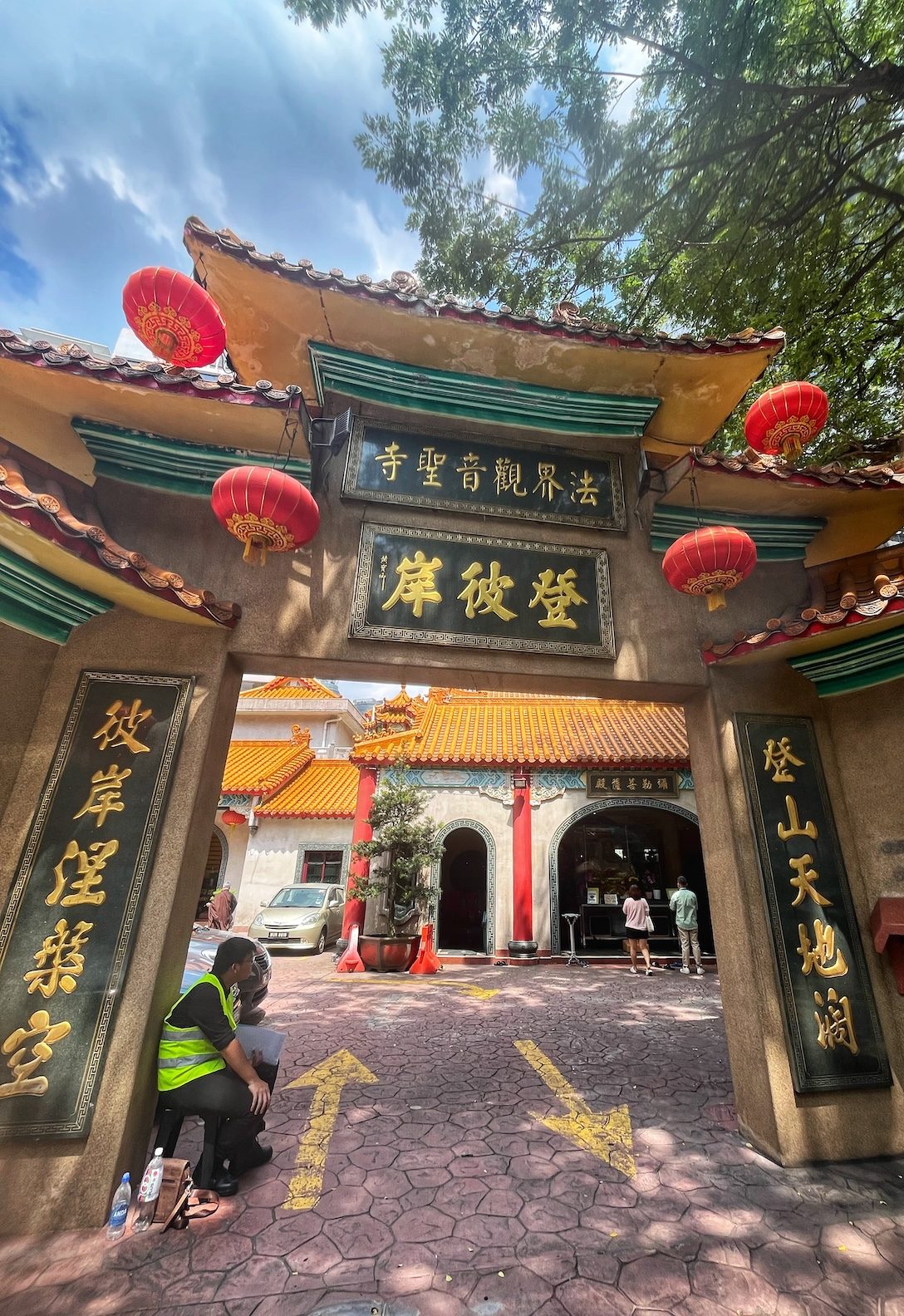 How Many Days Should You Spend in Kuala Lumpur? | dharma realm guan yin sagely monastery e1719576738129 Entrance to the Dharma Realm Guan Yin Sagely Monastery in Kuala Lumpur, Malaysia, featuring traditional Chinese architectural elements, red lanterns, and gold inscriptions. Two people are sitting near the entrance, and visitors can be seen entering the monastery.