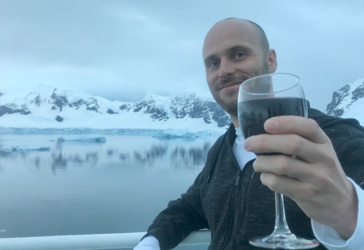 What To Expect on Your First Trip To Antarctica | drinking wine in Antarctica Drinking wine on an Antarctic cruise ship with a beautiful snowy landscape reflecting off the water