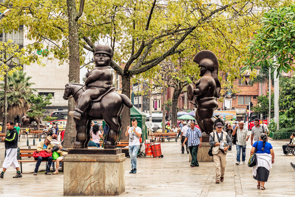 Where To Stay in Medellin: 7 Best Neighbourhoods! | el centro medellin Tourists walking by Botero sculptures located at Botero Plaza in Medellin, Colombia