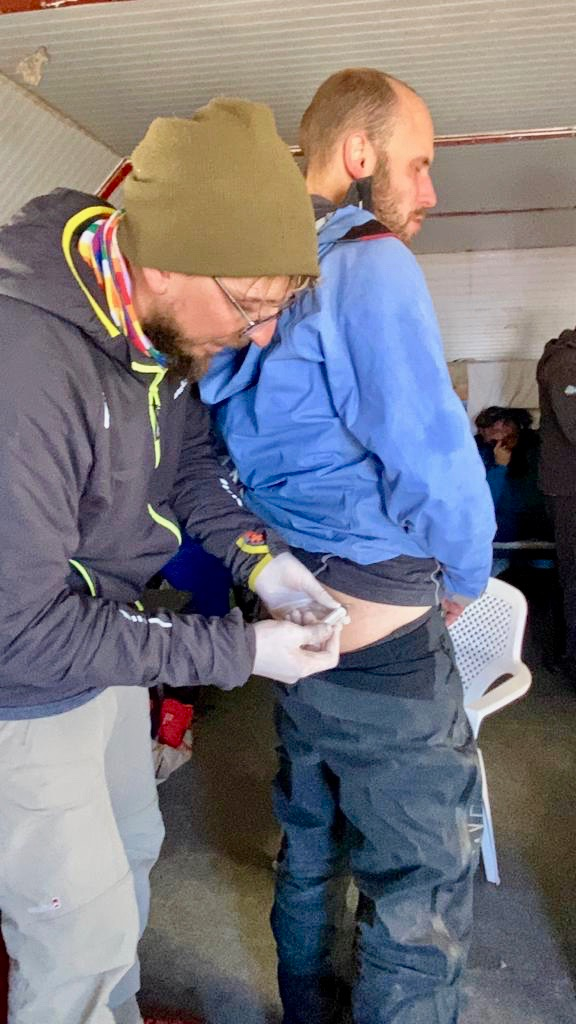 How Hard is it To Climb Aconcagua? | image 14 A climber on Aconcagua grimaces with altitude sickness as he receives a steroid injection into his buttocks during an Aconcagua expedition in Argentina