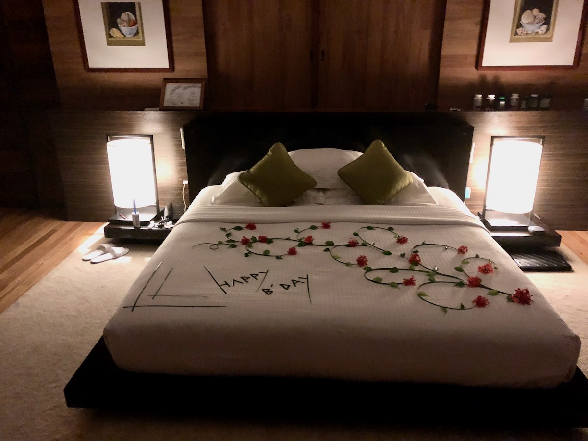 How To Plan a Trip To The Maldives | inside water villa Maldives A modern bedroom with "Happy Birthday" decorated on the bed with flowers